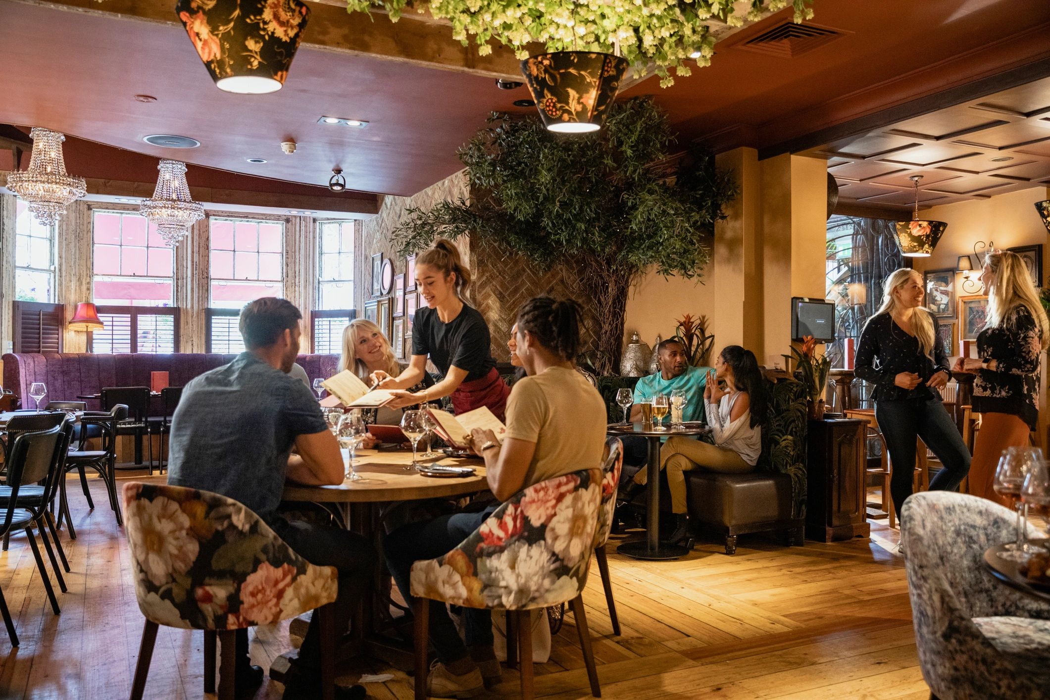 Guests dining in a warmly lit restaurant dining room, wide shot