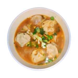 Steamed momo dumplings served with jhol achar (spiced dipping sauce), close-up on a clean background